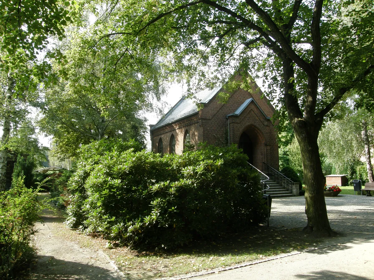 Backsteinkapelle mit Treppe unter Bäumen auf dem Friedhof Biesdorf